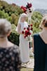 Bride beautifully standing in her vibrant red florals and simple bridal dress- Nelson Wedding