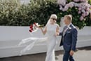 bride and groom lovingly walking wiht their vibrant red florals- Nelson Wedding